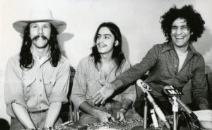 Tom Forcade (left) refuses to shake hands with Yippie activist Abbie Hoffman (right). Yippie Meyer Vishnu (center) tries to mediate an end to the Forcade-Meyer feud.